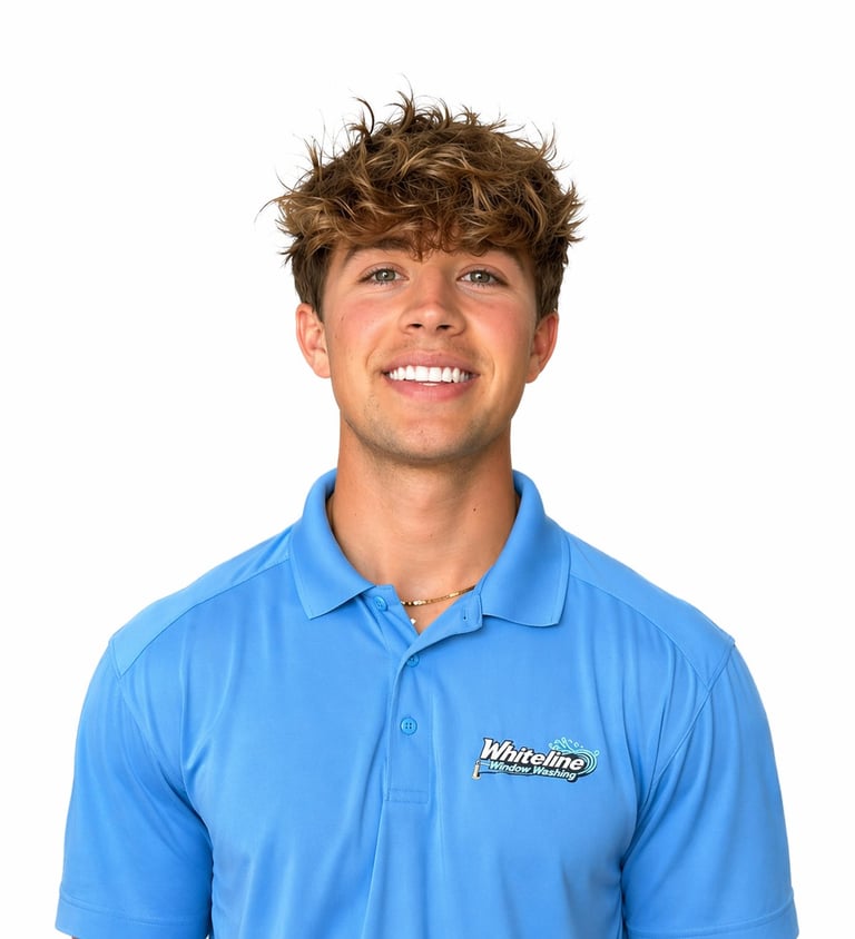 Young man with brown wavy hair smiling at camera, wearing a blue polo shirt with Whiteline logo on white background